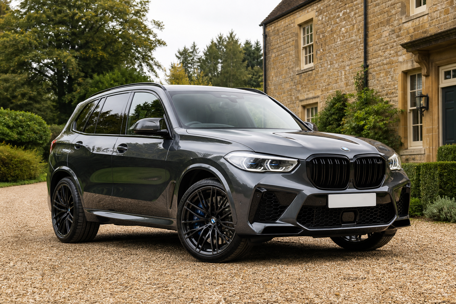 Graphite BMW X5 M Competition beside a warm-stone country house